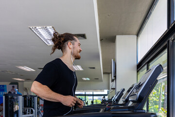 Smart fitness trainer shows how to use treadmill to improve leg strength and building muscles in a gym. A sport man is running on a treadmill to start his workout program.