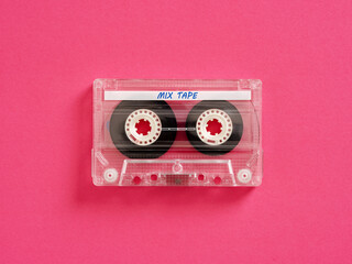 Transparent audio cassette lying on vivid pink background
