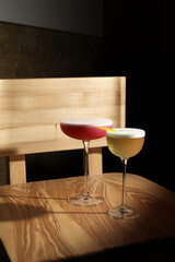 Two elegant cocktails on a wooden chair in soft light