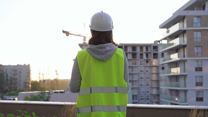 Female construction engineer is taking notes and writing on a clipboard while inspecting a...