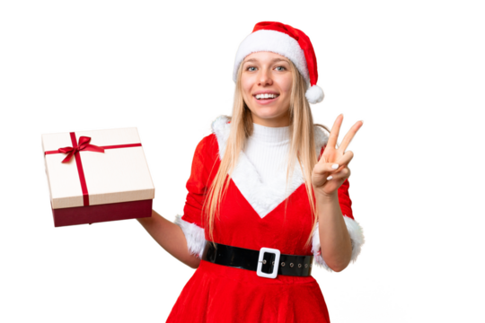Young blonde woman with christmas hat and holding a gift over isolated chroma key background smiling and showing victory sign