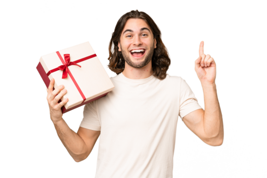 Young handsome man holding a gift over isolated background pointing up a great idea