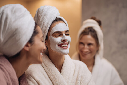 Friends enjoying a spa day. A woman with a face mask laughs with friends. Perfect for beauty, wellness, friendship, or selfcare concepts.