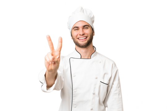 Young handsome chef man over isolated background smiling and showing victory sign