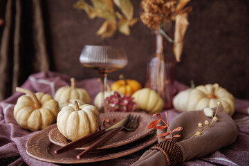 A cozy fall tablescape featuring white pumpkins, vintage plates, rustic napkins, and a glass goblet, creating a warm and festive atmosphere for Thanksgiving or seasonal gatherings