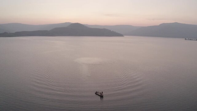 boat sailing in river hills in background sunset