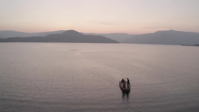 boat sailing in river hills in background sunset