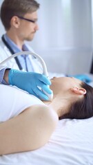 Obraz premium Doctor man wearing blue protective gloves is using ultrasound equipment on the neck of a patient woman, lying for examination. Medicine concept