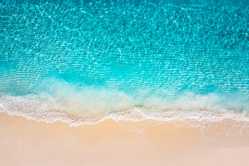 Aerial summer seascape with blue sea water waves crashing sandy beach shore top view from drone tropical ocean pattern bright light Mediterranean coast nature background surf detail sunny marine scene