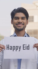 Vertical Photo of Indian Doctor Holding Happy Eid Poster