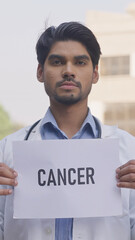 Vertical Photo of Indian Doctor Holding Cancer Poster