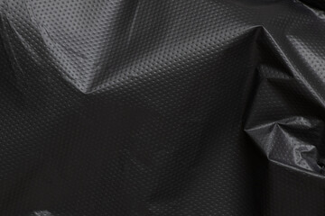 Obraz premium Crumpled black plastic film close up, texture of packaging material, plain polyethylene background with highlights and folds