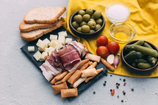 Close-up of a Spanish tapas selection including Serrano ham, cheese, gherkins, olives, tomatoes, toast and breadsticks