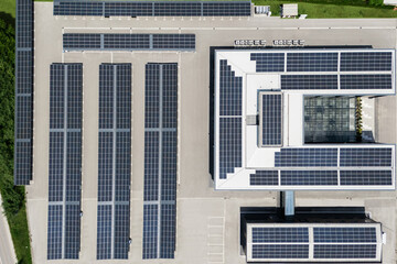 Aerial view of building with solar panels on a roof and parking space with solar canopies
