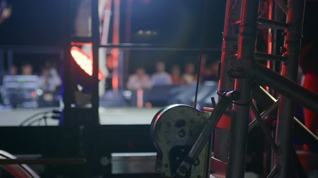 Cinematic side close-up of concert stage metal structure at night, blurred performer in background. Highlights technical setup, ideal for abstract, editorial, and backstage storytelling.