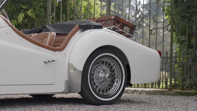 White triumph tr3 car parked in front of a gate. Action