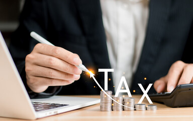 Tax concept.Wooden tax word on stack coin with businessman calculating the financial statement of...