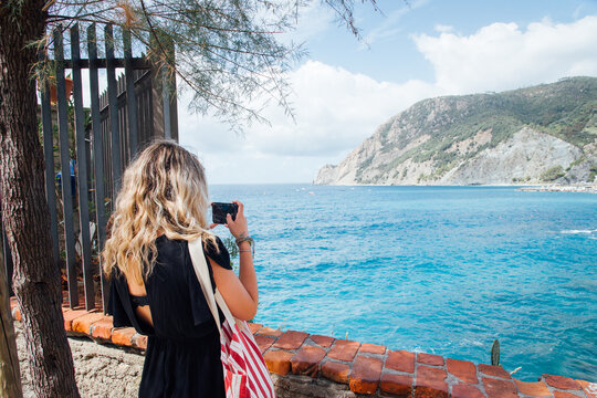 Jeune femme touriste photographiant la plage de Monterosso Al Mare des Cinque Terre. Vacances &agrave; la mer. Femme en &eacute;t&eacute; en m&eacute;diterran&eacute;e.