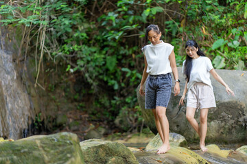Asian Indonesian Women Trekking Barefoot by River Rocks in Yogyakarta Jungle