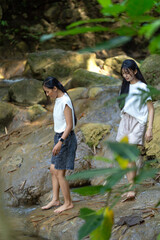 Asian Indonesian Women Trekking Barefoot by River Rocks in Yogyakarta Jungle