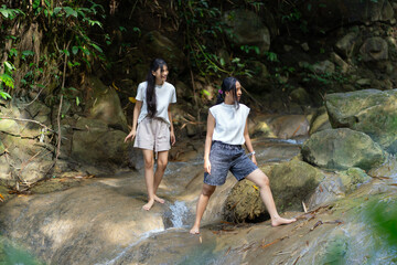 Asian Indonesian Women Trekking Barefoot by River Rocks in Yogyakarta Jungle