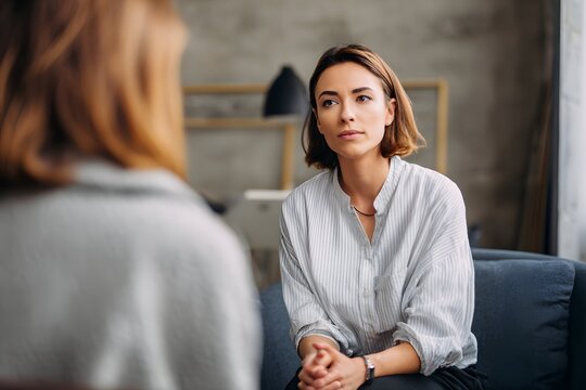 A compassionate therapist fostering trusting, attentive conversation in a sleek, serene studio.