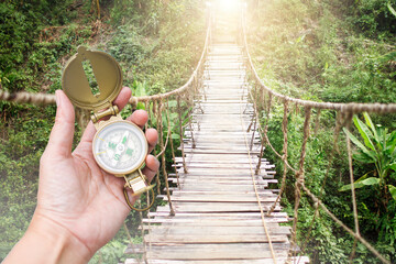 Compass in girl hand over hanging bridge and forest background, Navigation tool for tourism and...