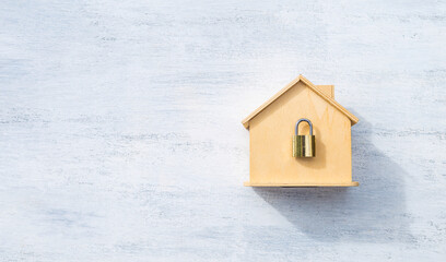 Wooden house model with padlock on white wood background, house safety and security, home lock