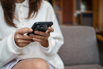 Close-up of a woman holding a smartphone while sitting on a sofa, showcasing modern technology and lifestyle.