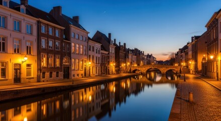 Obraz premium A charming european canal city at dusk, with historic buildings illuminated by streetlights reflecting on the calm water
