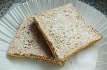 Two slices of whole wheat bread on a white paper plate. Healthy food.
