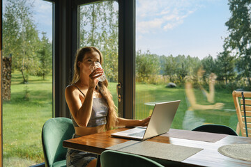 Woman working at bungalow in the woods on weekend and sipping mineral water