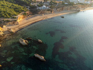 Aerial view of Praia do Alemão beach in Portimão, Algarve, Portugal, during a sunny morning with clear blue waters and golden sandy shore. Perfect for travel and nature themes.