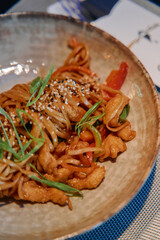 A Delectable Stir-Fry Dish Featuring Noodles, Tender Chicken, Fresh Vegetables, and a Flavorful Sauce Topped with Sesame Seeds and Green Onions
