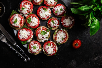 Appetizing appetizer of eggplants, tomatoes and basil in a plate on the table