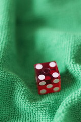 Un dado rojo para juego en una tela de color verde como fondo 