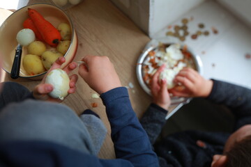 two child's hands cutting vegetables for salad close up