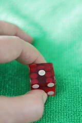 Una toma de cerca de un dado rojo para juego en una tela de color verde como fondo 