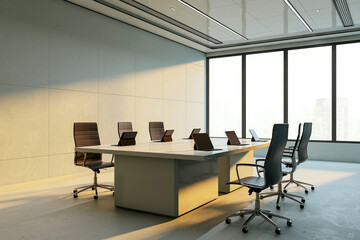 Modern corporate boardroom interior with sleek furniture, laptops on desk, large windows and sunlight casting shadows across the office space. 3D Rendering