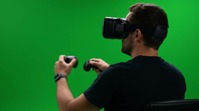 Man wearing a vr headset and holding controllers against a green screen in a studio setting