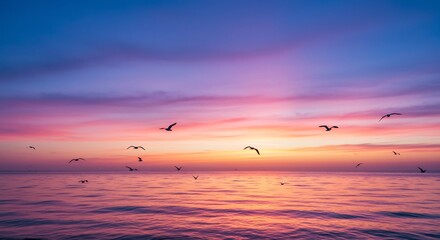 Silhouettes of birds flying over a calm sea with a dramatic pink and purple sunset sky.