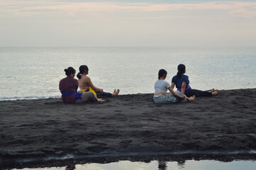 Transitioning smoothly, the girls straighten both legs forward while sitting on the sand, preparing...
