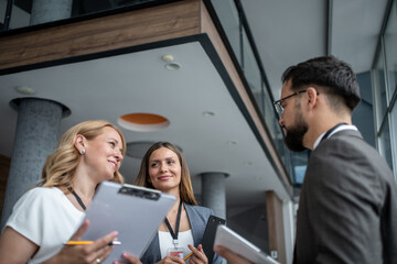 Businesspeople discussing work in modern office building lobby