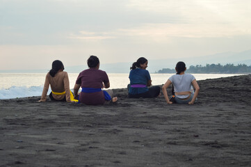 Viewed from behind, the four girls return to a centered seated position, as one turns her head...