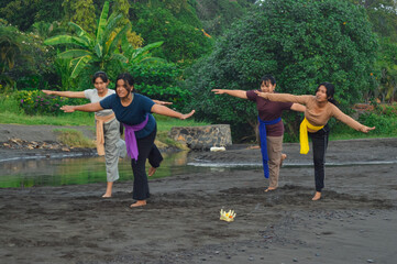 All four girls lean forward with arms outstretched, balancing on their left foot while performing a...
