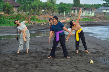 The teenage girls end the yoga round and return to a neutral standing posture, inhaling deeply as...