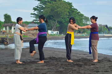Each pair of girls lifts their right leg forward while holding hands, executing a yoga balance move...