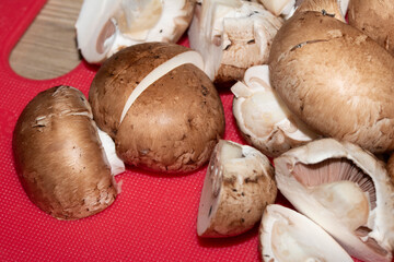 CLose up of chopped sliced mushrooms on red choopping board