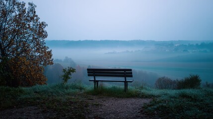 Obraz premium Foggy Morning in the Countryside with a Bench Facing the Horizon