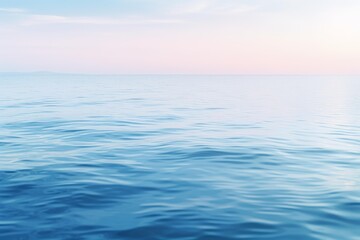 Fototapeta premium Tranquil blue ocean reflecting a serene pastel colored sunrise sky, creating a peaceful and minimalist seascape